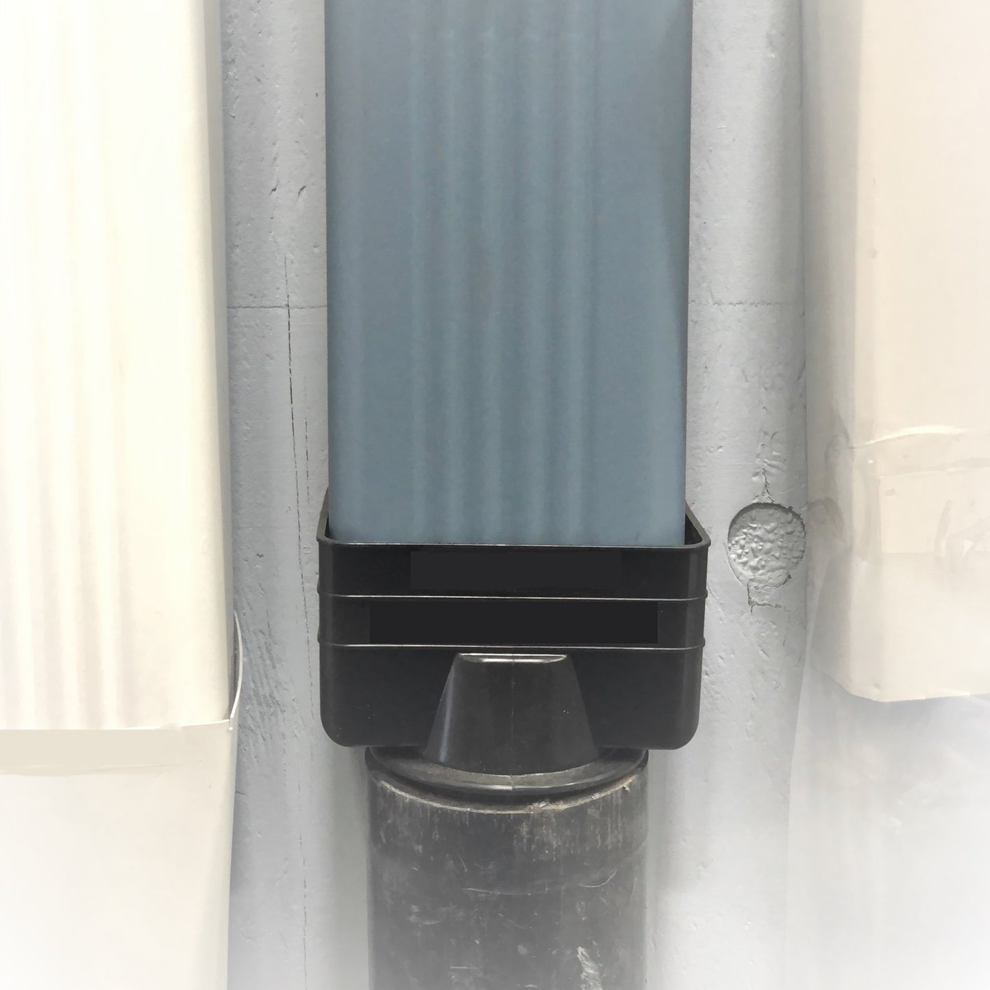 Black vinyl downspout reducer installed on a gutter system for smooth water flow.