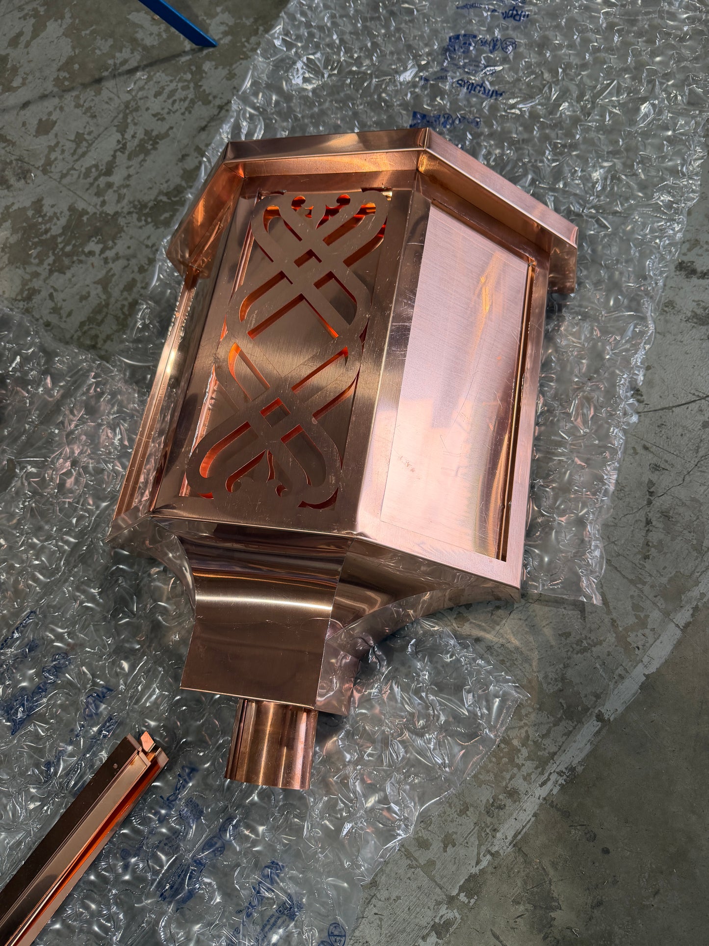 Ornamental copper conductor head with scroll cut decorative lattice front panel 18x8.5x20 inch leader head rain collector box featuring peaked gabled top faceted hexagonal body and 2x3 oval downspout outlet in bright mill finish 16 oz copper by GutterAll Damascus Oregon