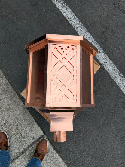 Ornamental copper conductor head with scroll cut decorative lattice front panel 18x8.5x20 inch leader head rain collector box featuring peaked gabled top faceted hexagonal body and 2x3 oval downspout outlet in bright mill finish 16 oz copper by GutterAll Damascus Oregon