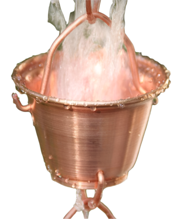 Close-up of copper bucket cup rain chain with water flowing through.