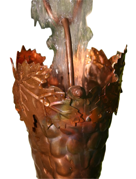 Water flowing through a copper grapevine rain chain cup with detailed leaf design.