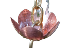 Detailed view of water cascading through pink lotus copper rain chain cup.