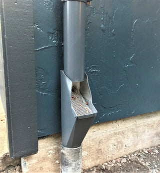 Gray GutterAll downspout cleanout screen installed on a house exterior.