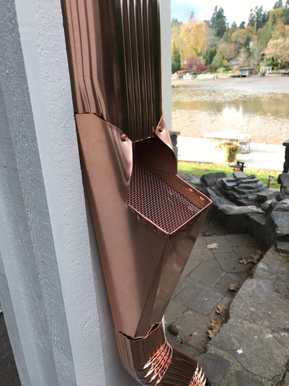 Copper GutterAll downspout cleanout screen installed near a scenic outdoor view.