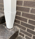 Installed white aluminum downspout reducer connecting to a gutter system.