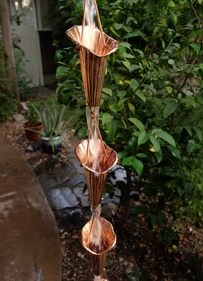Cala Lily Cups Copper Handcrafted copper Lotus Flower Rain Chain showcasing intricate petal design and water flow in a garden setting