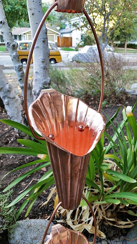 Handcrafted copper Lotus Flower Rain Chain showcasing intricate petal design and water flow in a garden setting