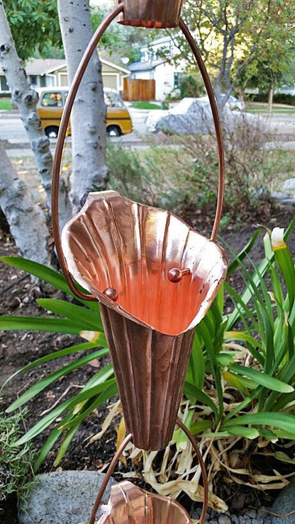 Handcrafted copper Lotus Flower Rain Chain showcasing intricate petal design and water flow in a garden setting