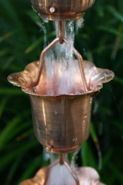 Copper-toned buttercup rain chain with water cascading through the cups.