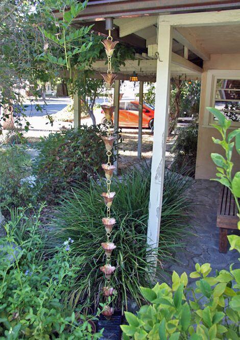 Cast Flower 2.0 rain chain installed on a house, enhancing the garden decor.