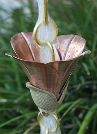 Cast Flower 2.0 copper rain chain in use, surrounded by greenery.