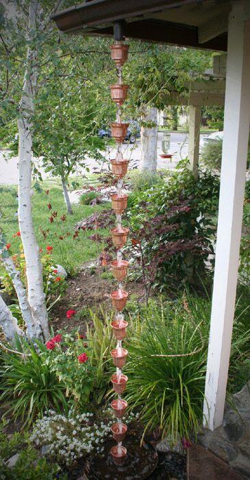 Full view of a copper rain chain installed in a garden setting.