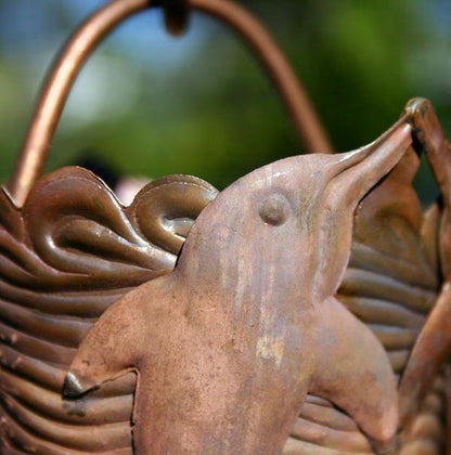 Detailed view of dolphin motif on copper rain chain cup.
