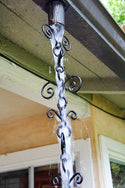 Functional French flower rain chain directing water from a gutter with stylish black metal swirls.