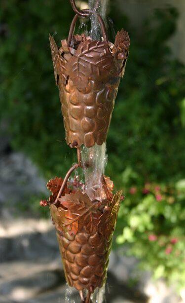Two copper grapevine rain chain cups linked together with water cascading through.