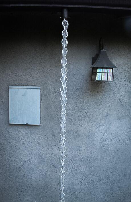 Full view of silver hooked rings rain chain installed as a decorative downspout.