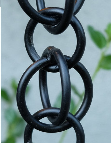 Close-up of black hooked rings rain chain with a modern outdoor setting.