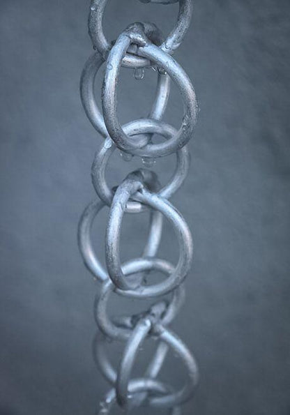 Silver hooked rings rain chain with water droplets on a gray background.
