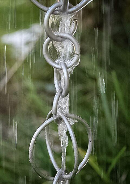 Silver rain chain with water streaming through interlocking rings.