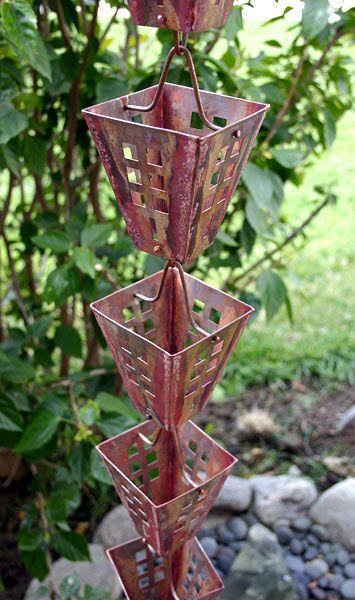 Decorative copper rain chain with Japanese box rain cups in a lush garden.