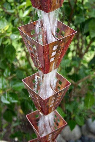 Close-up of copper rain chain with water cascading through Japanese box rain cups.