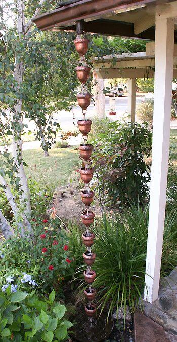 Full-length view of oaknut cup rain chain installed in a lush garden.