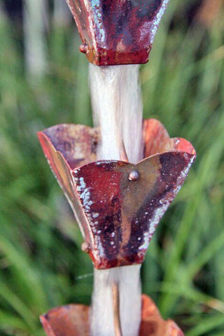 Copper petal top rain chain with water flowing through cups.