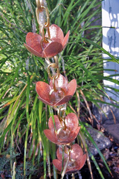 Pink lotus copper rain chain with multiple handcrafted cups in outdoor setting.