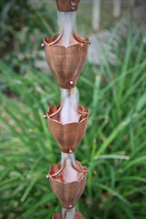 Multiple copper funnel cups forming a rain chain with water flowing.