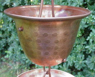 Single copper bell cup from a rain chain with a spotted hammered design.