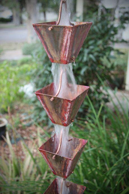 Traditional copper patina rain chain with square cups creating a water feature.