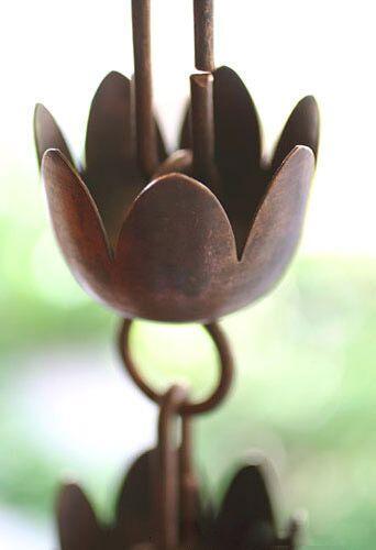 Decorative tulip copper rain chain with a floral design, shown in natural light.