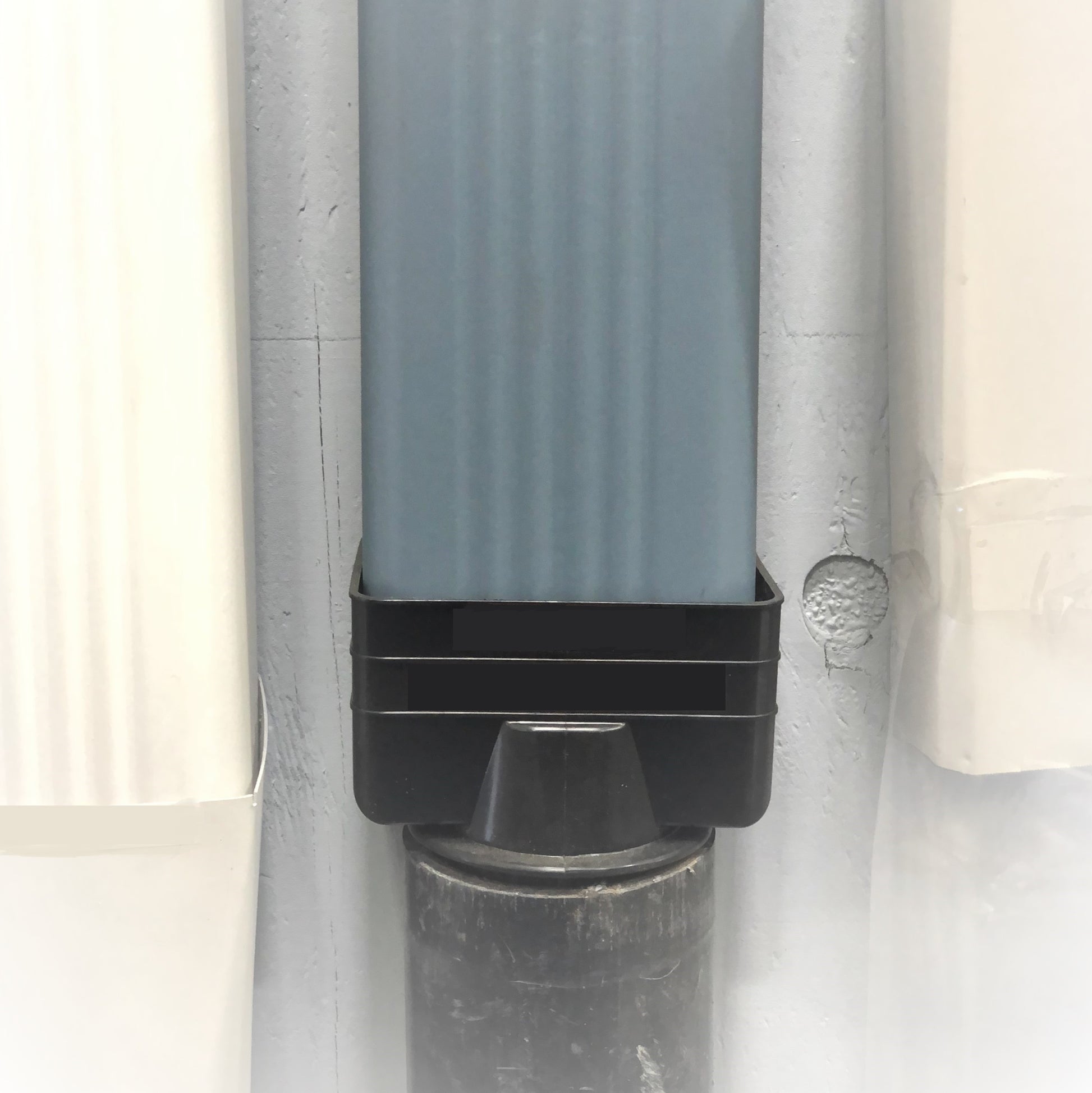 Black vinyl downspout reducer installed on a gutter system for smooth water flow.