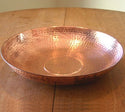 Decorative copper rain chain anchoring bowl with a dotted hammered design.