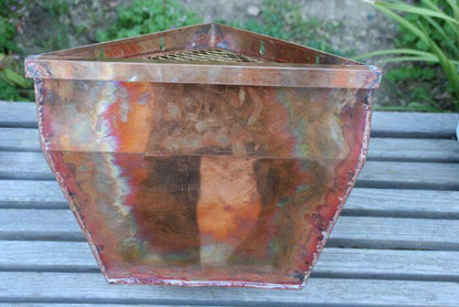 Rear view of copper corner leaderhead with natural patina on wooden surface.
