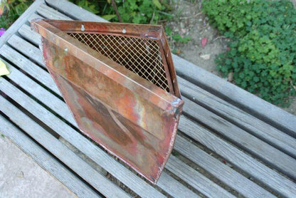 Angled view of triangular copper leaderhead showcasing mesh screen.