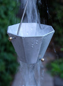 Octagonal aluminum rain chain cup with water flowing through, showcasing its modern design.